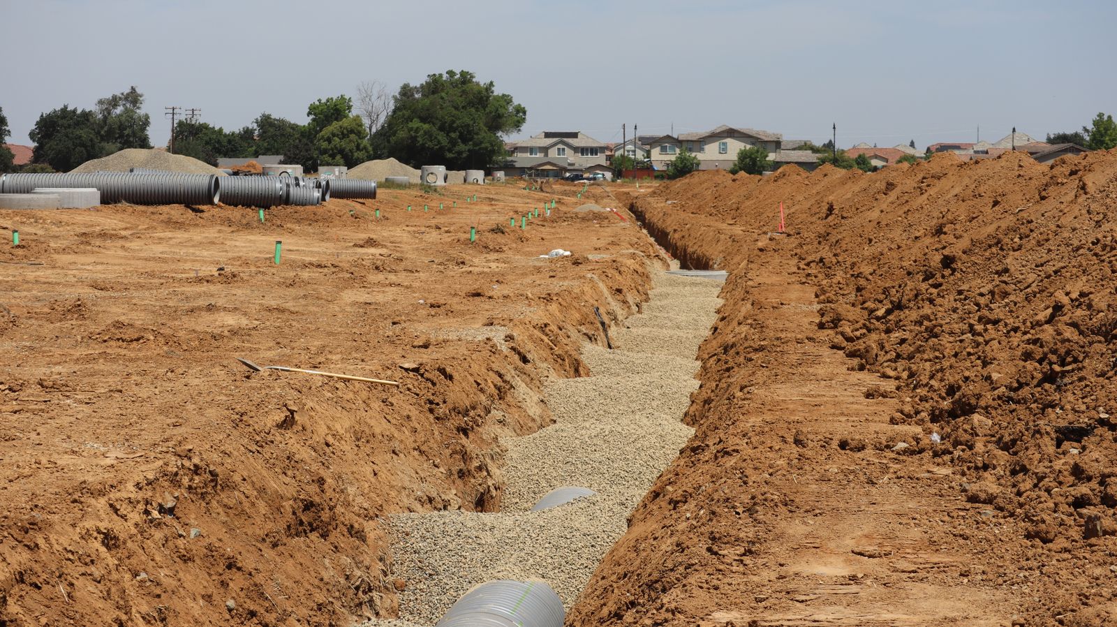 Suburban sewer work site showing the minimal excavation access pits used for trenchless sewer repair