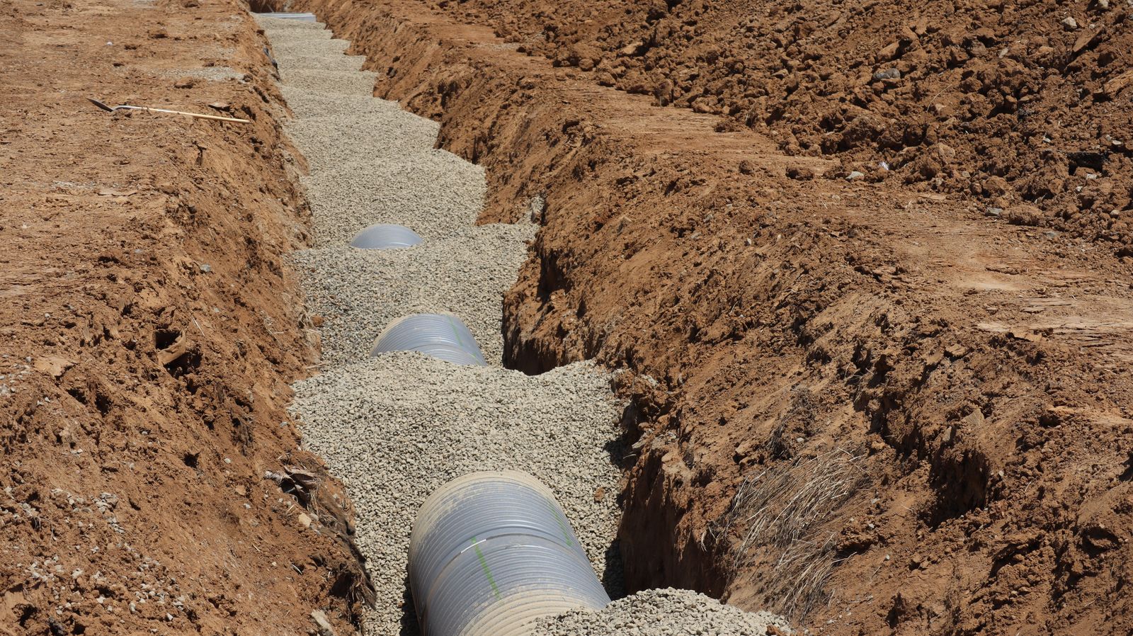 New sewer pipe being installed in an open trench during a residential sewer line replacement